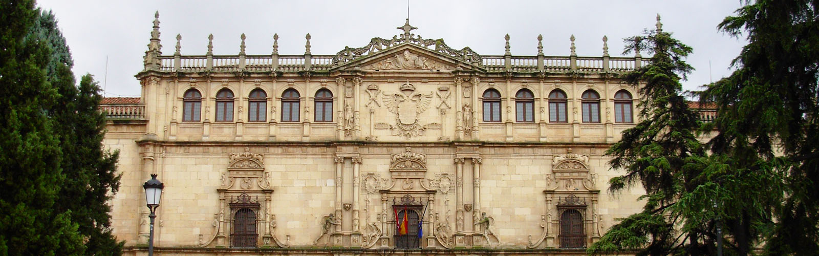 A stone building with an ornate facade, framed on both sides by trees.